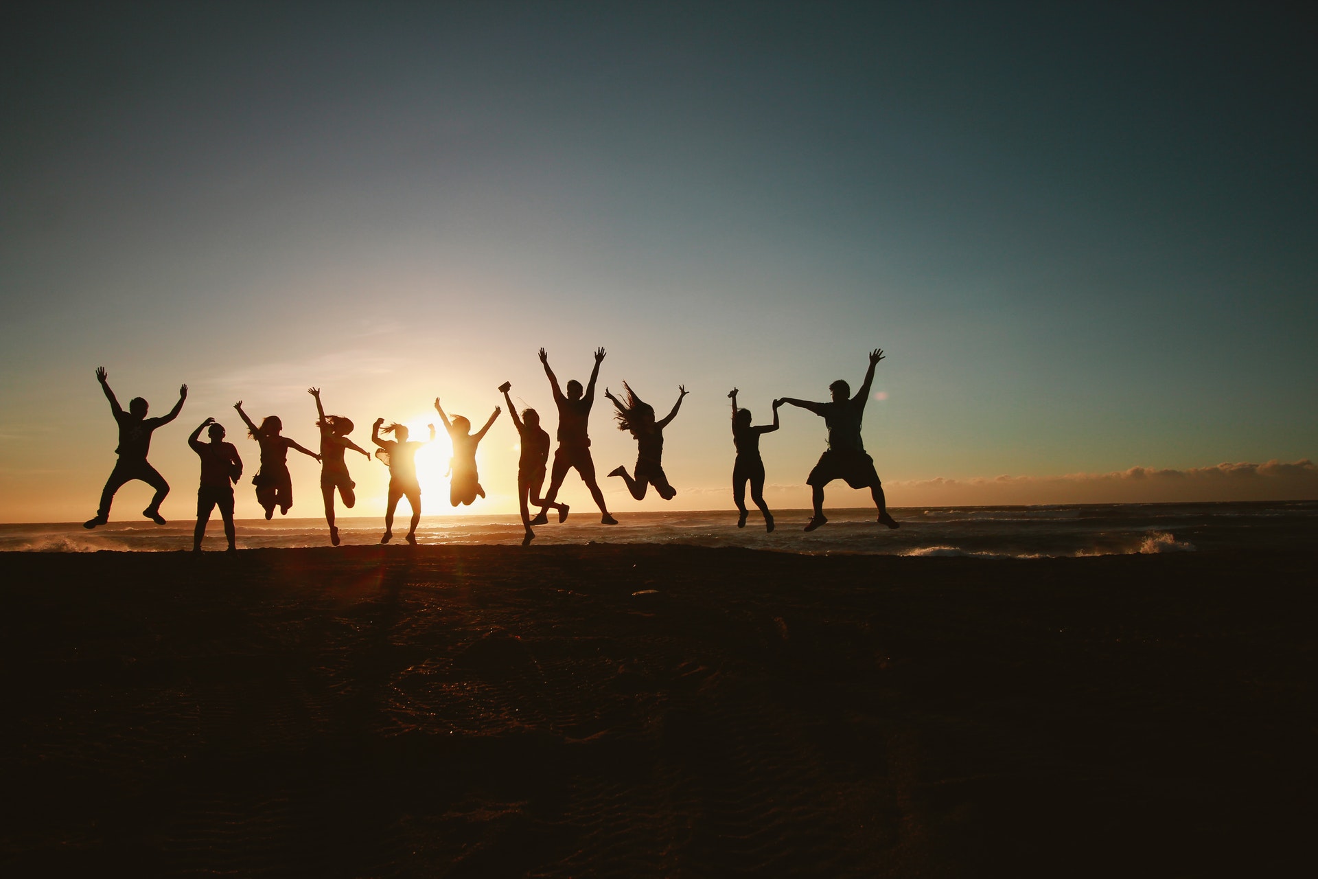 Silhouette of 12 people in a line, jumping for joy