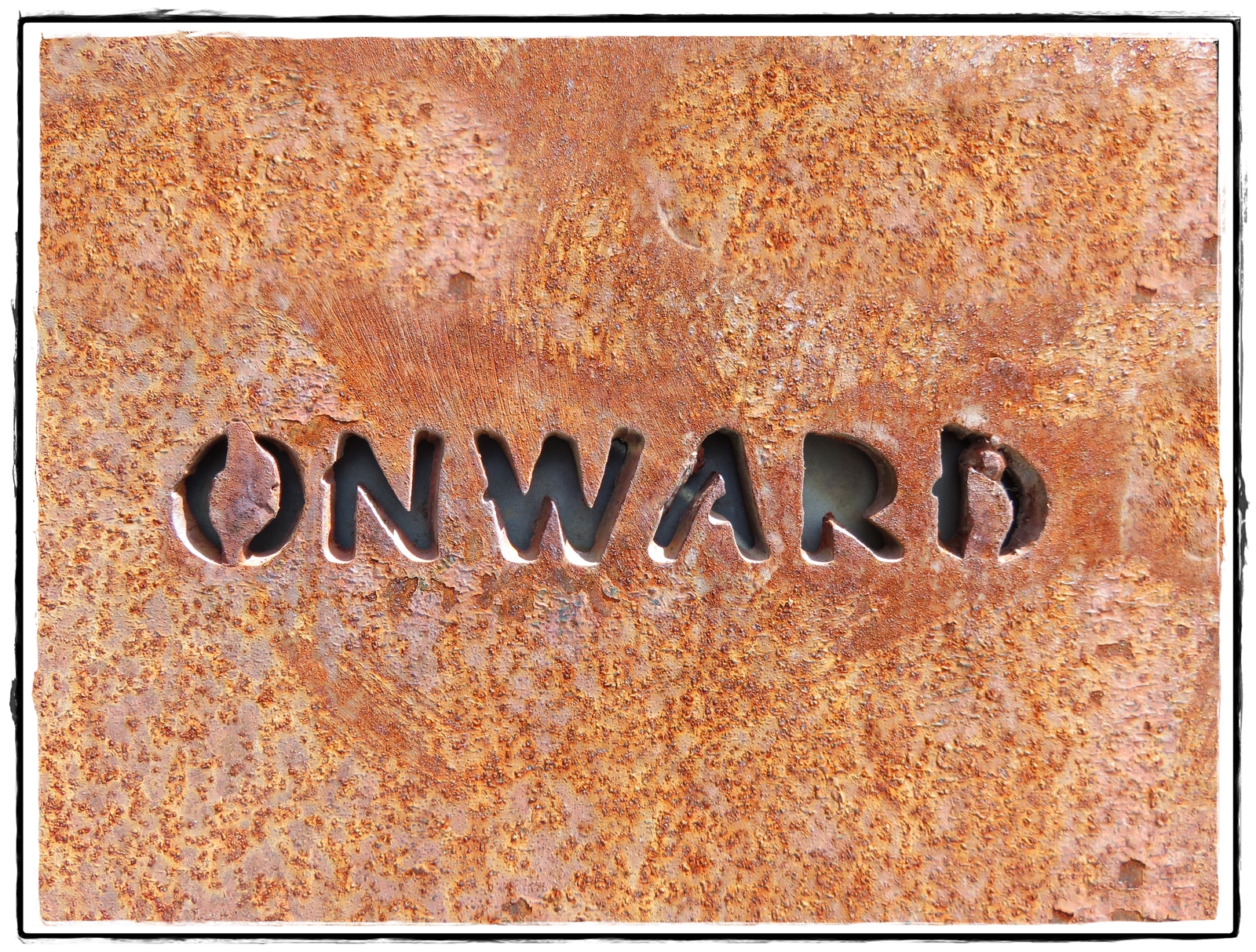 The word "onward" chiseled into rust-colored stone