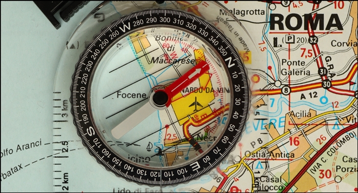 Close-up of a map with a compass resting on top of it