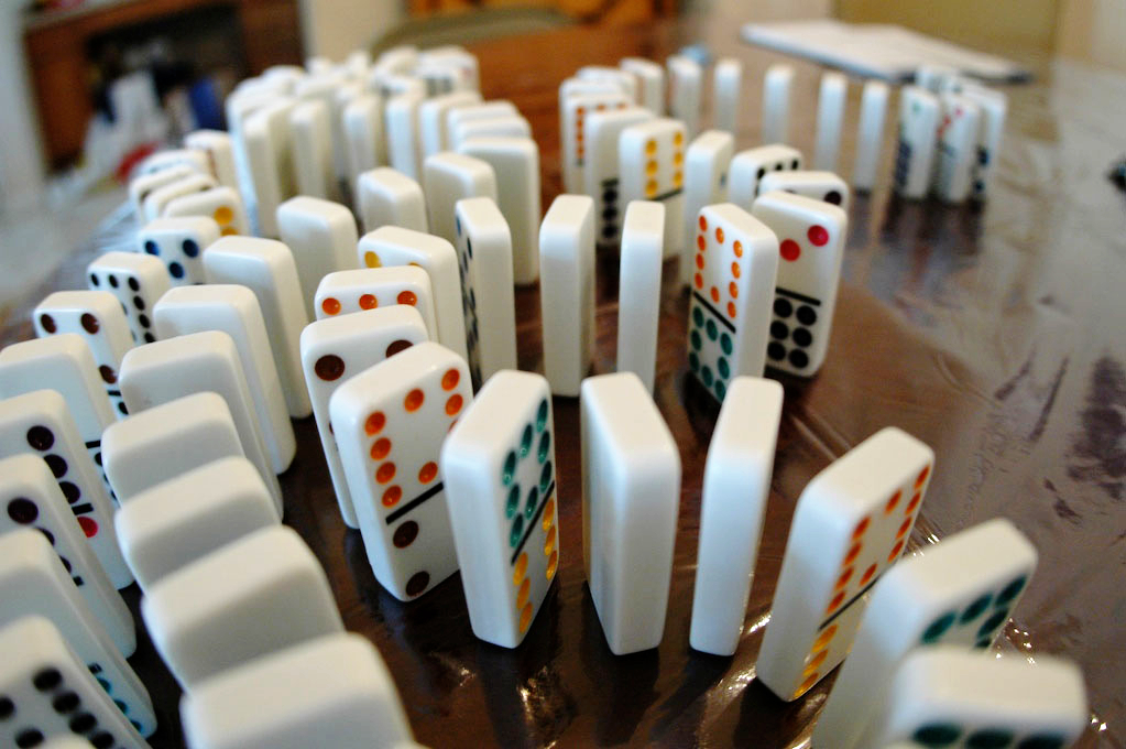 Dominoes standing on end in a line, waiting to be toppled