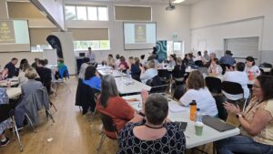 Hildy speaking at the front of a room full of people
