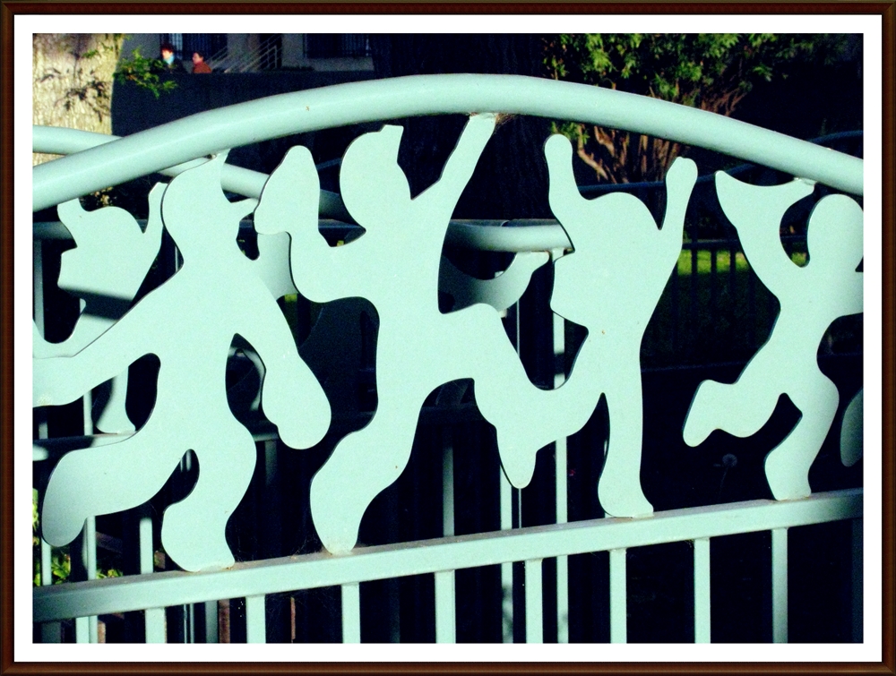 Metal stenciled cut-outs of kids jumping happily, in a light turquoise green