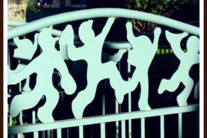 Metal stenciled cut-outs of kids jumping happily, in a light turquoise green